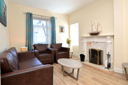 a living room with leather furniture and a fireplace at Burnside in Tighnabruaich