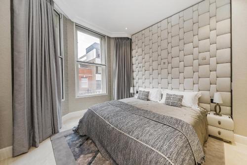 ein Schlafzimmer mit einem großen Bett und einem großen Fenster in der Unterkunft Piccadilly Green Park Apartment in London