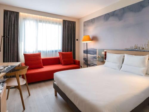 Habitación de hotel con cama y sofá rojo en Novotel Madrid City Las Ventas, en Madrid