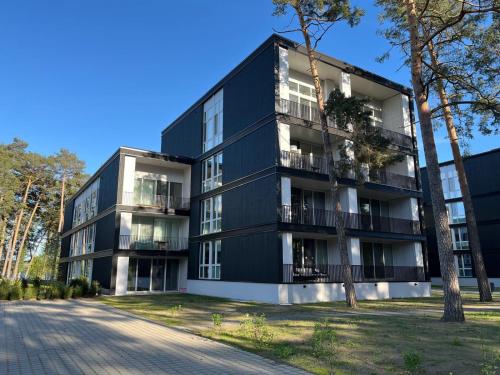 ein schwarzes Gebäude mit einem Baum davor in der Unterkunft My Marina Apartment mit Pool und Sauna am See in Bad Saarow