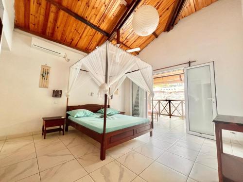 Schlafzimmer mit Himmelbett und Holzdecke in der Unterkunft Résidence Kambana in Nosy Be