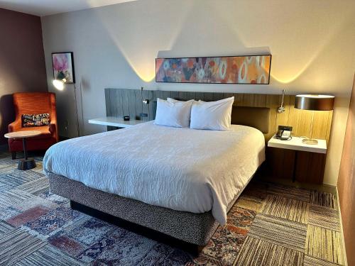 a hotel room with a bed and a chair at Hilton Garden Inn Oconomowoc in Oconomowoc