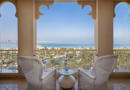 a room with two chairs and a view of the ocean at Waldorf Astoria Ras Al Khaimah in Ras al Khaimah