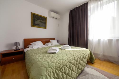 a bedroom with a green bed with towels on it at Apartament Family Rivulus 9 in Baia Mare