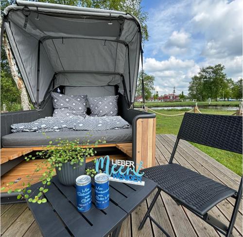 un gazebo con un letto e una sedia su un ponte di Schlafstrandkorb a Südbrookmerland
