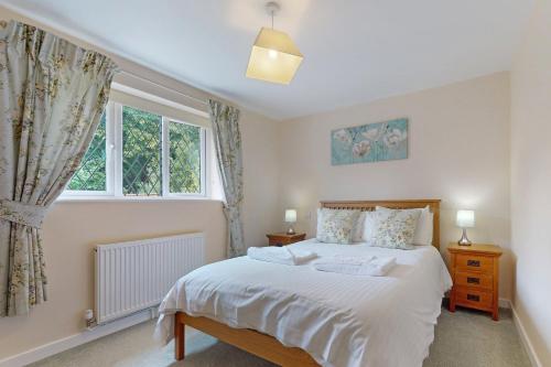 a bedroom with a large white bed and a window at Plum Tree Cottage, Porlock in Porlock