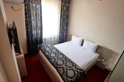 1 dormitorio con cama, ventana y TV en КZO en Shymkent