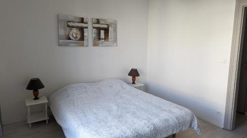 a white bedroom with a bed and two lamps at Les tourelles in Dieppe