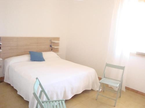 a bedroom with a white bed and two chairs at Cala Vigliena Il Sole Negli Occhi in Punta Braccetto