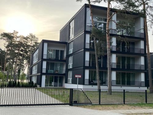 ein schwarzweißes Apartmenthaus mit einem Zaun in der Unterkunft My Marina Apartment mit Pool und Sauna am See in Bad Saarow