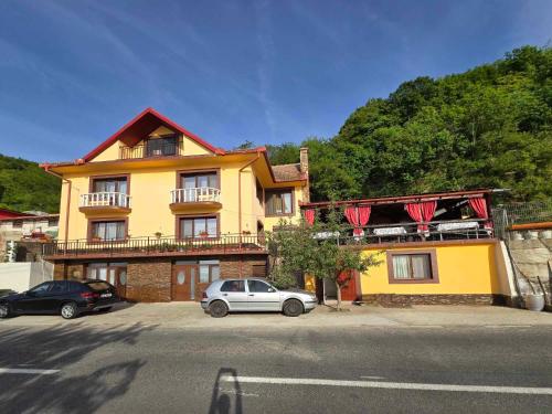 un bâtiment jaune avec des voitures garées devant dans l'établissement Casa Ștefania, à Pescari