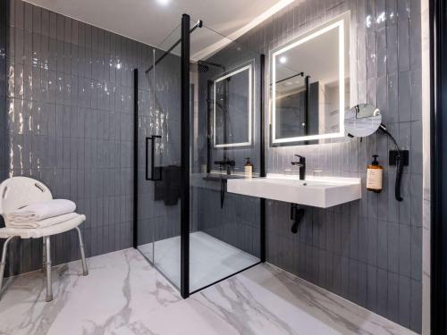 a bathroom with a sink and a shower with a mirror at Mercure Chantilly Resort & Conventions in Chantilly