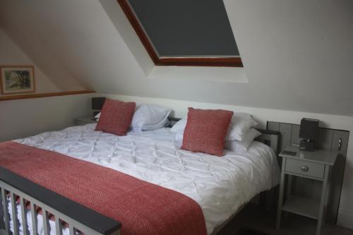a bedroom with a bed with white sheets and red pillows at The Lodge in Newcastle Emlyn