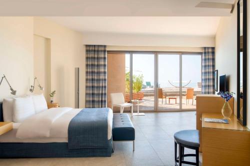 Habitación de hotel con cama y sala de estar. en Kempinski Hotel Ishtar Dead Sea en Sowayma