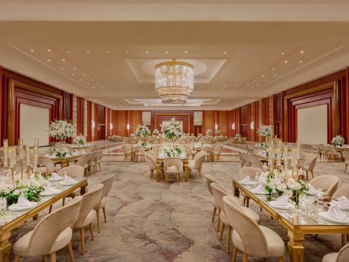 um salão de banquetes com mesas e cadeiras e um lustre em Mövenpick Hotel Cairo - Media City em Cidade 6 de Outubro