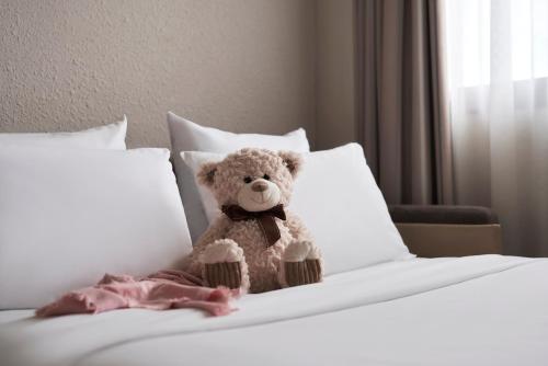 a teddy bear sitting on top of a bed at Novotel Athens in Athens