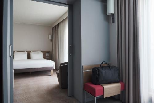 a room with a bedroom with a bed and a suitcase at Novotel Athens in Athens