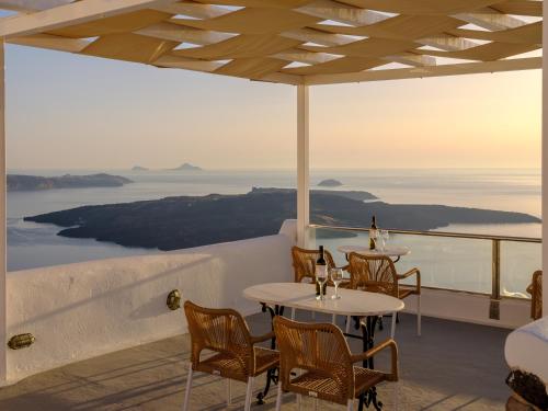 a restaurant with tables and chairs and a view of the ocean at Vallas Apartments & Villas in Firostefani
