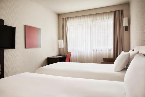 a hotel room with two beds and a window at Novotel Athens in Athens