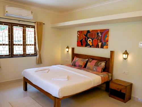 a bedroom with a large bed and a painting on the wall at Cielo in Palolem