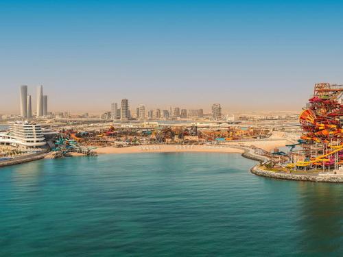uitzicht op een strand met een stad op de achtergrond bij Rixos Premium Qetaifan Island North in Doha