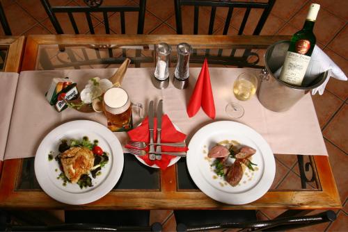 a table with two plates of food and a bottle of wine at Penzion FAJN *** in Pardubice