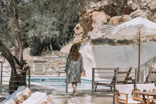 Una mujer con un vestido caminando por una piscina en Zos Suites, en Kanakis