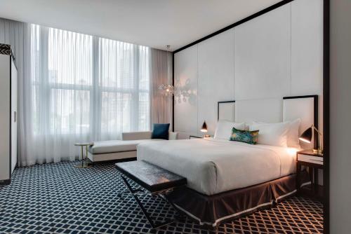 um quarto com uma grande cama branca e uma cadeira em The Inchcolm em Brisbane