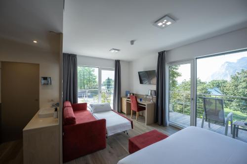 a hotel room with a red couch and a large window at Hotel Bellariva in Riva del Garda
