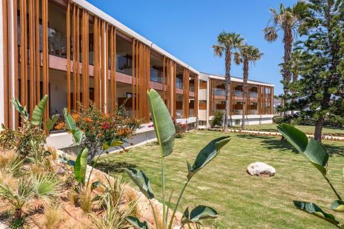 an exterior view of a building with palm trees at Isla Brown Chania Resort, Curio Collection by Hilton in Stavros