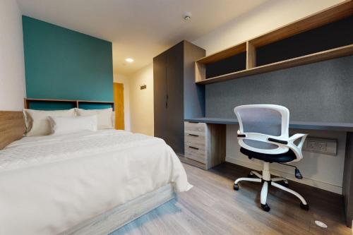 a bedroom with a bed and a desk and a chair at Canvas Wembley in London in London