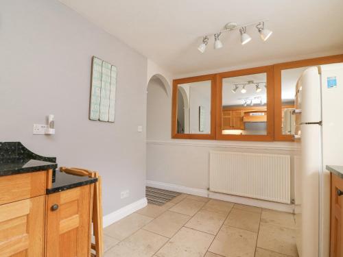 uma cozinha com paredes brancas e armários de madeira em Harbourside Cottage em Weymouth