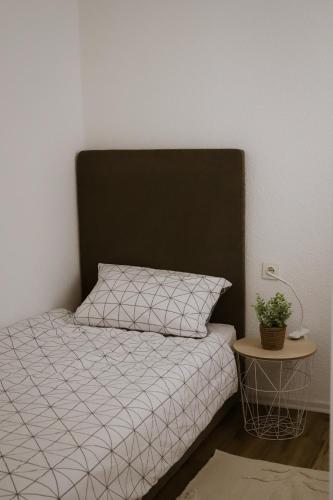 a bed with a black and white comforter and a table at Apartman BUCO in Đakovo