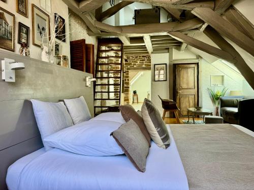 um quarto com uma cama grande com lençóis brancos e almofadas em Le Relais des Ducs : centre historique Dijon em Dijon