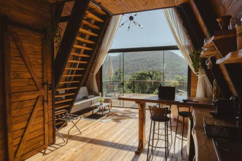 um quarto com uma mesa e uma grande janela em Cabana romântica com hidromassagem próx ao centro. em Nova Petrópolis