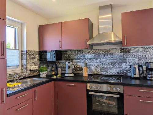 a kitchen with red cabinets and a sink at Premiumferienhaus Mara in Hasselfelde