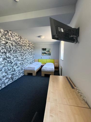 a room with two beds and a tv on the wall at Sport hotel Sletiště in Kladno