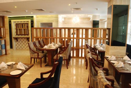 Glades Hotel في شانديغار: مطعم فيه طاولات وكراسي في الغرفة