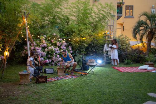 a group of people sitting in a garden at night at HOPESTEL Secret Garden Napoli in Naples