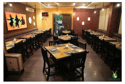 una sala da pranzo con tavoli lunghi e sedie in un ristorante di HOTEL JODHA THE GREAT ad Agra