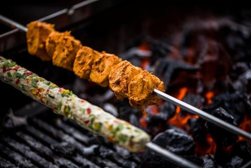 a group of skewers cooking food on a grill at Glades Hotel in Chandīgarh