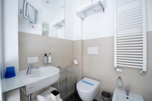 a bathroom with a sink and a toilet and a mirror at Hotel Bellariva in Riva del Garda