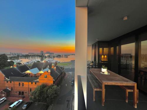 a balcony with a table and a view of a city at Harbour Towers, Newcastle's Luxe Apartment Stays in Newcastle