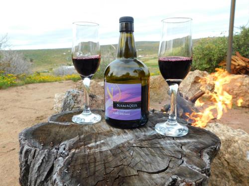 dos copas de vino tinto sentado en un tronco de árbol en Nuwefonteinskop Lodge, en Kotzesrus