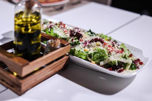 a salad in a bowl on a table with a bottle of beer at Hotel Frojd - Beach Front Resort in Shëngjin