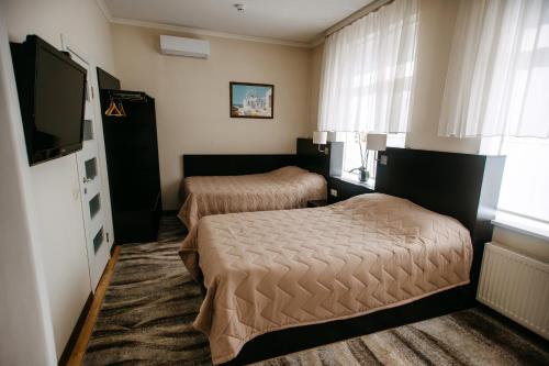 a hotel room with two beds and a flat screen tv at Summit Villa in Chişinău