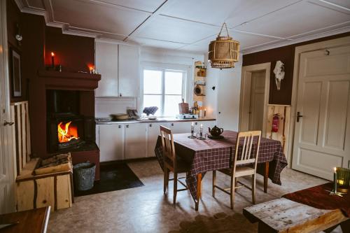 a kitchen with a dining table and a fireplace at Off the grid in the abandoned village of Ejheden in Voxnabruk