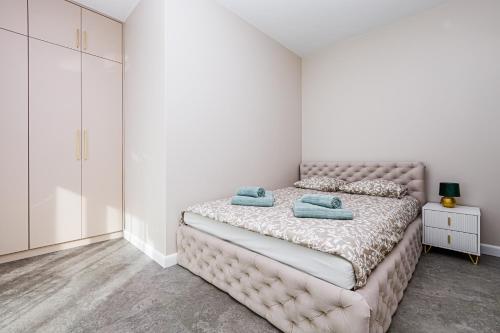 a white bedroom with a bed with blue towels on it at Szum Fal Rewal in Rewal