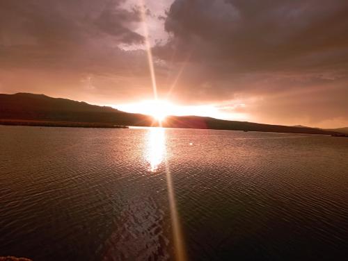 a sunset over a body of water with the sun setting at Titicaca Magical Lodge Peru in Puno