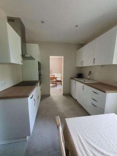 une cuisine avec des armoires blanches et une table à l'intérieur dans l'établissement Gite de Charme des 3 Allures, à Serley